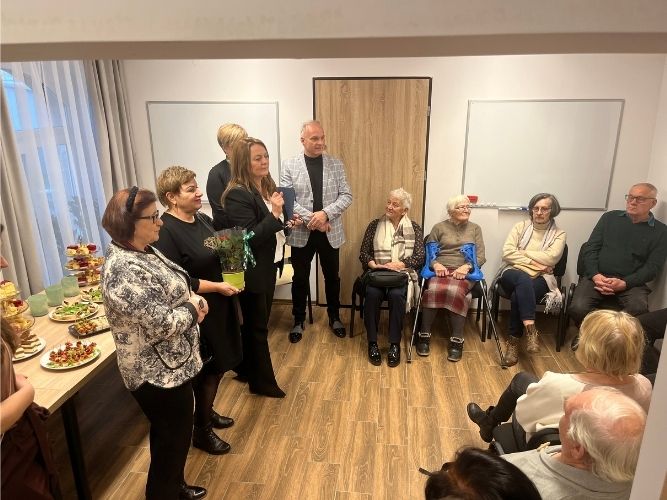 grupa osób podczas przemowy; siedzący seniorzy i inni goście