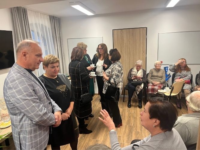 grupy ludzi rozmawiających w klubie - część siedzących, część stojących